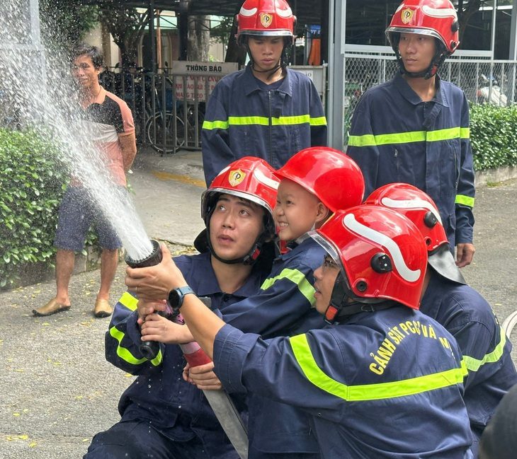 Bé Trung Quân cười khoái chí khi cùng các chiến sĩ Phòng Cảnh sát phòng cháy chữa cháy và cứu nạn cứu hộ (PC07) Công an TP.HCM cầm lăng phun "chữa cháy" - Ảnh: BVCC