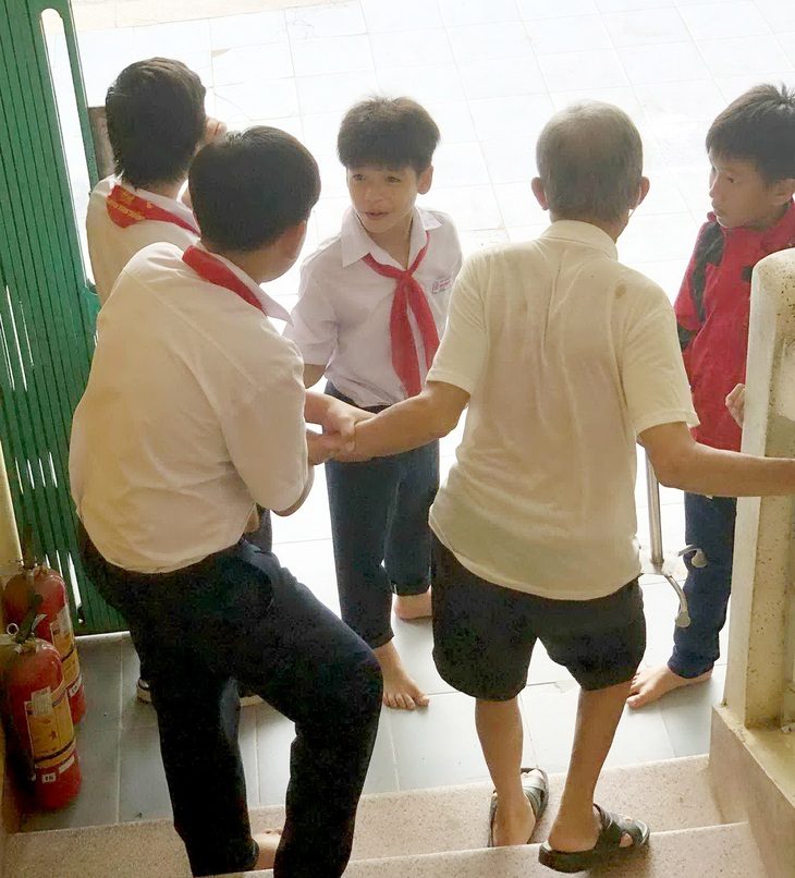 Các bạn nhỏ dìu cụ ông xuống cầu thang - Ảnh: Tác giả cung cấp