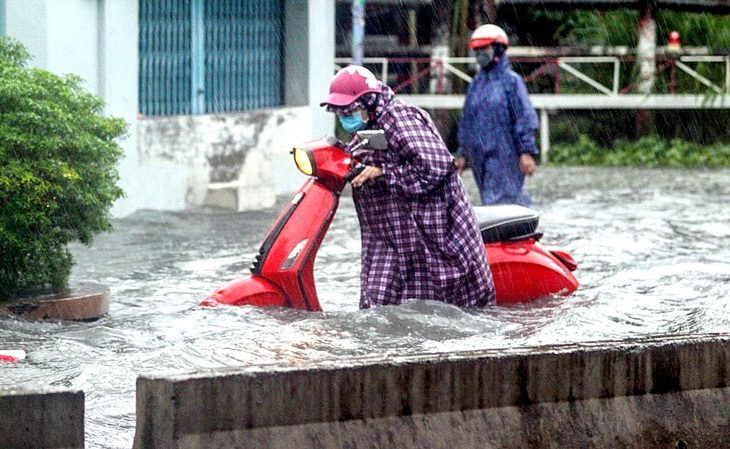 Người dân vất vả di chuyển qua đoạn ngập trên đường Tô Ngọc Vân (TP Thủ Đức) - Ảnh: PHƯƠNG QUYÊN