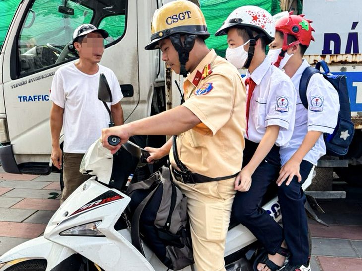 Cảnh sát giao thông đưa 2 nam sinh đến trường sau khi lập biên bản xử lý vi phạm nồng độ cồn - Ảnh: H.Q.